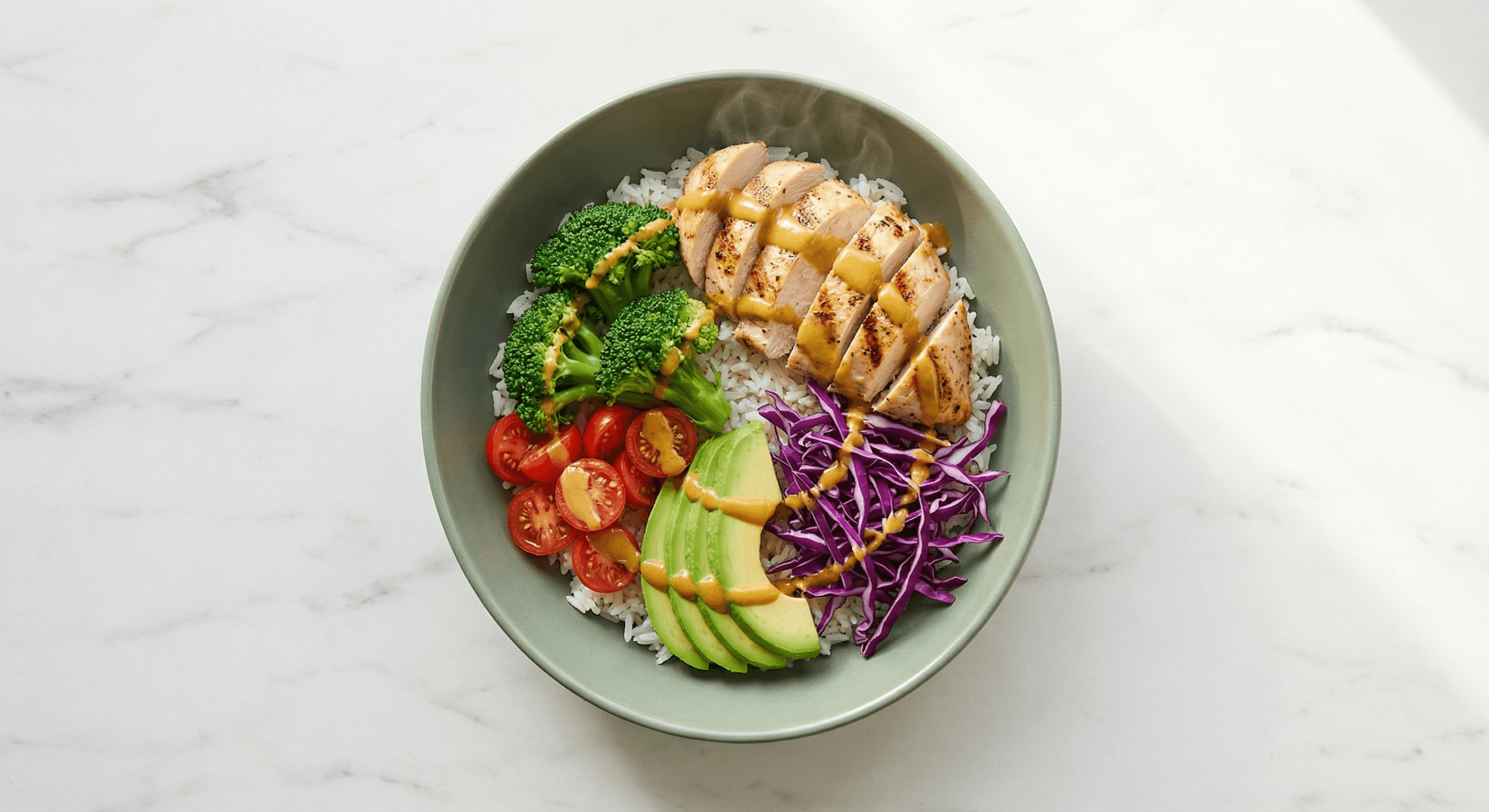 Signature healthy meal prep bowl with grilled chicken, fresh vegetables, rice, and golden tahini sauce